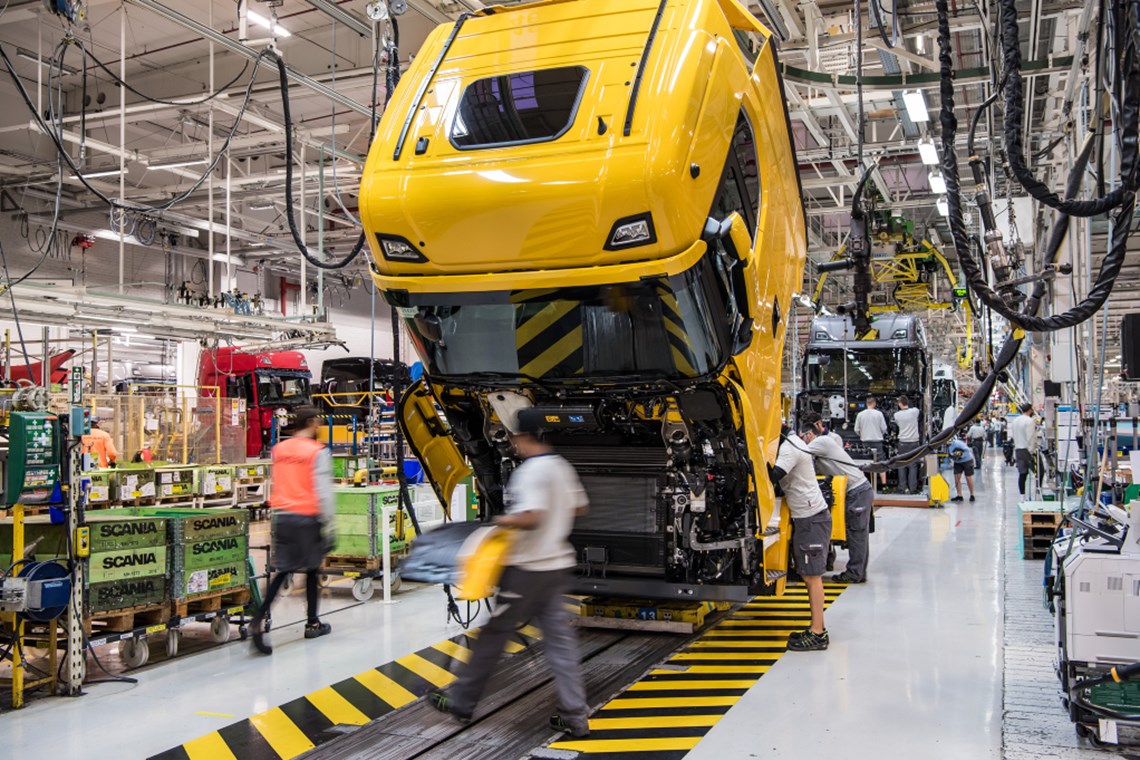 Workers assembling truck chassis at an assembly line Workers assembling truck chassis at an assembly line